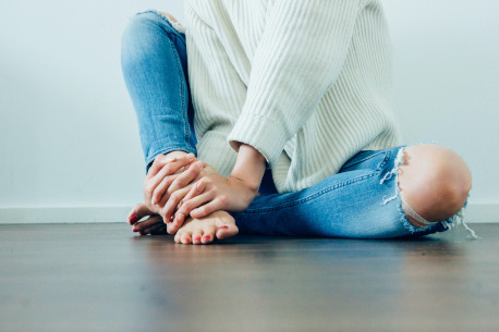 A person sits on wooden flooring